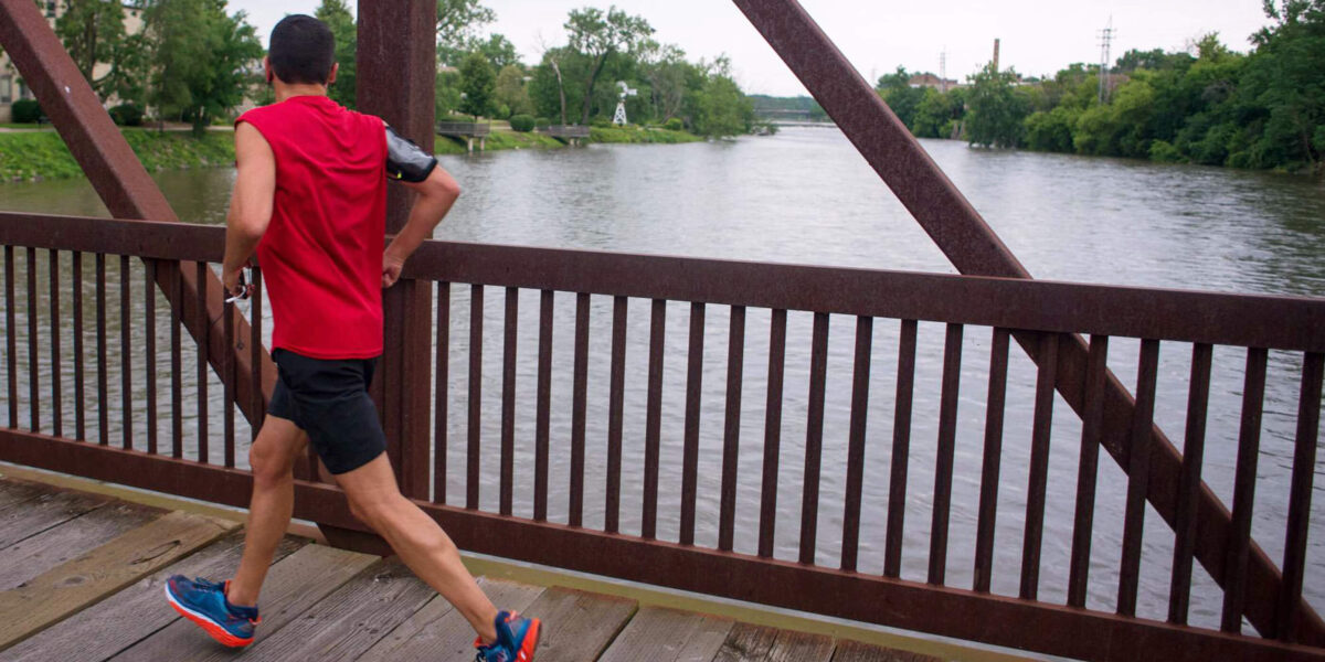 Jogger on pedestrian bridge over riverway